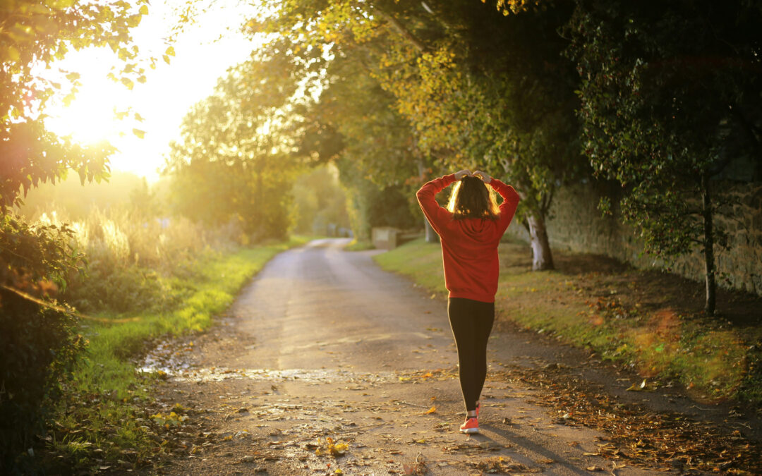 Person walking on a road at dusk with hands on head